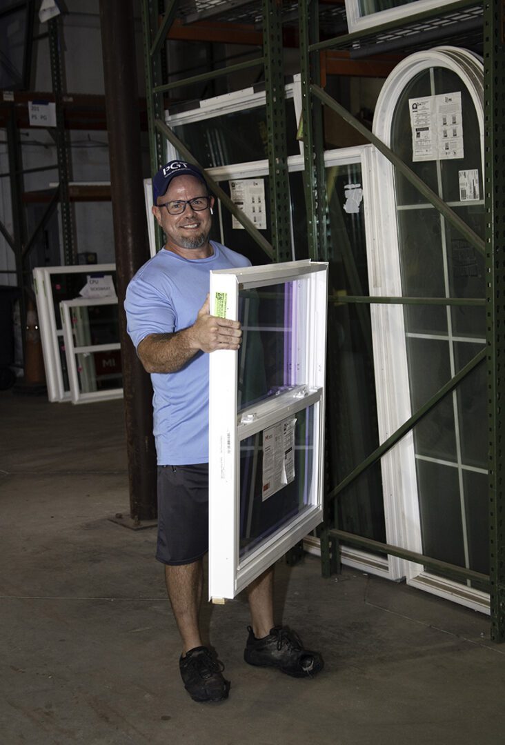 weathermaster-team-member-holding-window-in-warehouse